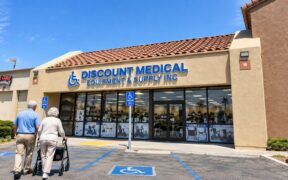 Discount-Medical-–-Mobility-Equipment-Supplies-storefront-in-Costa-Mesa-California-with-an-older-couple-walking-toward-the-medical-supply-store-using-a-rollator.